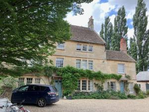 a car parked in front of a large house at Deco Artist Cottage in Tytherton Lucas