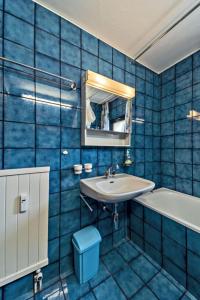 a blue tiled bathroom with a sink and a tub at Chesa Chamuotsch - Celerina in Celerina +8 photos