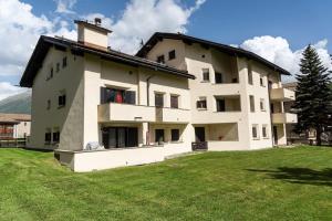 a large building with a grassy field in front of it at Chesa Chamuotsch - Celerina in Celerina