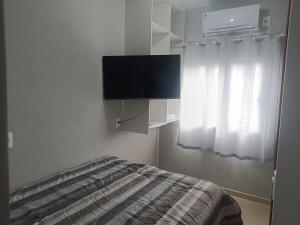 a bedroom with a bed with a tv and a window at Loft mobiliado in Joinville