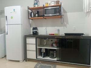 a kitchen with a counter with a microwave and a refrigerator at Loft mobiliado in Joinville