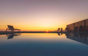 a pool with chairs and the sunset in the background at Orient Villas Deluxe in Volimes