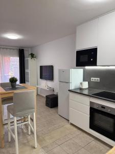 a kitchen with white appliances and a table with a chair at Casa de Rufio With Pool Tenerife in Puerto de Santiago