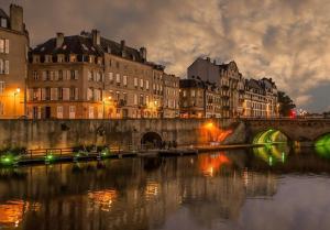 a bridge over a river in a city at night at Le Cocon de la Cathédrale au cœur de Metz in Metz
