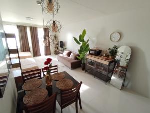 a living room with a table and chairs and a couch at Puerto Princesa Studio Condo with 2 Large Beds, Balcony, Pool & Gym in Puerto Princesa City