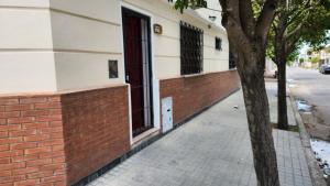 a brick sidewalk next to a building with a tree at El Tesoro Cordobés in Córdoba