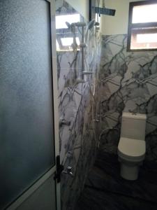 a bathroom with a toilet and a stone wall at Aluthwewa Gate in Angunakolapelessa