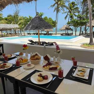 a table with food on it next to a pool at Amani Palms by Manolo Beach Resort in Uroa