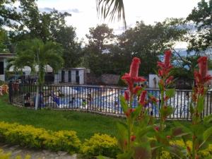a fence in front of a pool with red flowers at Llano grande rivera in Rivera