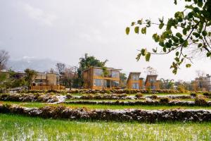 a garden with houses in the background at Qudrat - Boutique Hostel & Cafe in Bīr