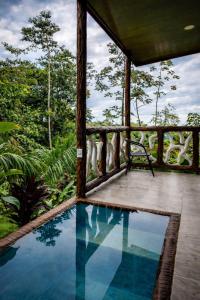 a house with a swimming pool and a bench on a porch at Chato Arenal Lodge in Fortuna