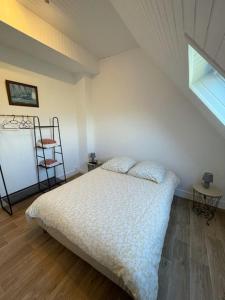 a bedroom with a white bed and a window at Le OUESSANTIN in Lampaul +3 photos