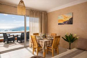 a dining room with a table and a view of the ocean at 2BR Luxury Apartment-Heart Of Taghazout, Private Beach Access, Panoramic View, Remote Work 100Mbps, Walk to Restaurants in Taghazout +33 photos
