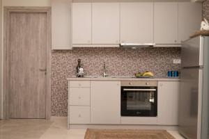a kitchen with white cabinets and a stainless steel refrigerator at Beach House Lefkes B in Zakynthos