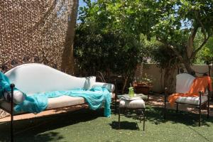 a garden with a couch and two chairs and a tree at Beach House Lefkes B in Zakynthos