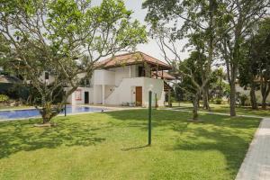 a garden with a swimming pool and a building at Hibiscus Beach Hotel & Villas in Kalutara