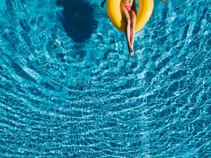 a woman floating on a banana in a swimming pool at Ninfa Sul Mare Apartments - Piscina con Area Relax e Parcheggio Gratuito in Capo Vaticano +105 photos