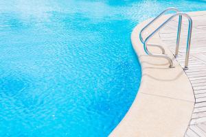 a pool with a metal bench next to the water at Ninfa Sul Mare Apartments - Piscina con Area Relax e Parcheggio Gratuito in Capo Vaticano