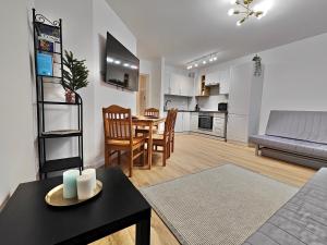 a living room with a dining table and a kitchen at Apartament Bursztynowy Jantar 2 pokojowy z ogrodzonym tarasem przy nadmorskim lesie in Jantar