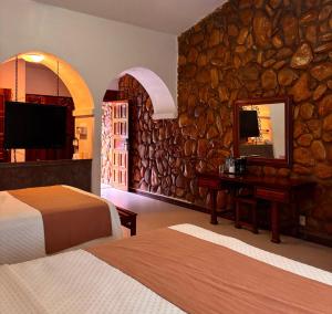 ein Hotelzimmer mit zwei Betten und einer Steinwand in der Unterkunft Hotel Nututun Palenque in Palenque