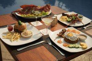 a table with three plates of food and glasses of wine at Hibiscus Beach Hotel & Villas in Kalutara