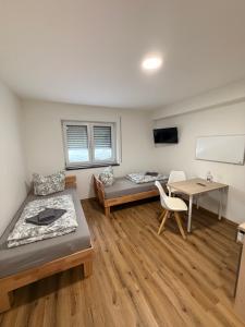 a room with two beds and a table and a desk at Tiny Stay Guesthouse - Würzburg in Würzburg