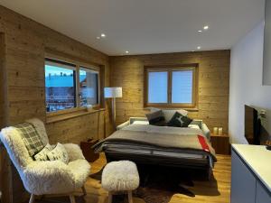 a bedroom with a bed and a chair and windows at Chalet Sofia in Bettmeralp