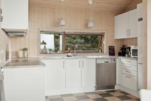a kitchen with white cabinets and a sink and a window at Seaside Cottage At Bønnerup Strand in Glesborg