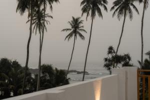 a view of the ocean from a balcony with palm trees at Orca Dickwella in Dickwella