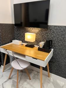 a desk with a lamp and a tv on a wall at Hotel Garda in Rome
