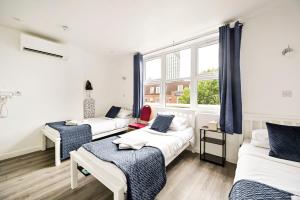 a room with three beds and a window at City London Hotel in London