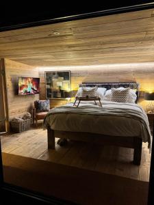 a bedroom with a large bed with a wooden wall at The Goose In The Woods - With Lakeside Sauna in Wellesbourne Hastings