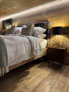 a bedroom with a large bed with a wooden wall at The Goose In The Woods - With Lakeside Sauna in Wellesbourne Hastings