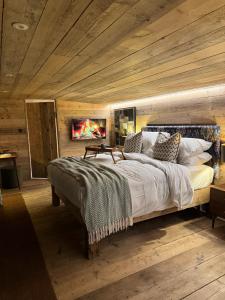 a bedroom with a large bed with wooden ceilings at The Goose In The Woods - With Lakeside Sauna in Wellesbourne Hastings