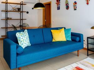 a blue couch with colorful pillows in a living room at Central Caldas w/ AC & Fast Net in Caldas da Rainha