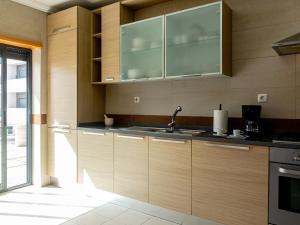 a kitchen with wooden cabinets and a sink at Central Caldas w/ AC & Fast Net in Caldas da Rainha