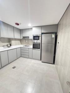 a kitchen with white cabinets and a stainless steel refrigerator at شقة في دار المشاعر in Mecca +34 photos