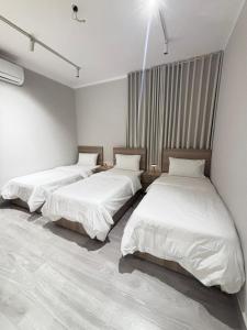 three beds in a room with white walls at شقة في دار المشاعر in Mecca