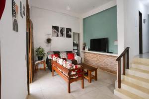 a living room with a couch and a tv at Pouso Ravenala - Refúgio do viajante in Paraty