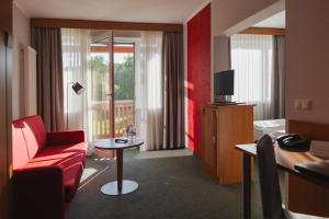 a hotel room with a red chair and a television at Gästehaus Kloster Nimbschen in Grimma
