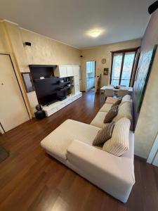 a living room with three white couches and a flat screen tv at La casa di Alice in Orbassano