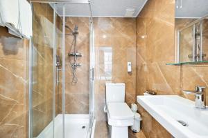 a bathroom with a shower and a toilet and a sink at City London Hotel in London +75 photos