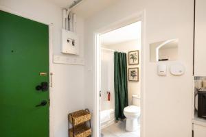 a bathroom with a green door and a toilet at Quiet & Walkable - Stampede, BMO, Nightlife & Eats in Calgary