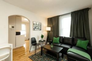 a living room with a black couch and green pillows at Quiet & Walkable - Stampede, BMO, Nightlife & Eats in Calgary