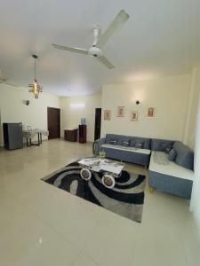 a living room with a blue couch and a rug at Rosewood Cottage in Karachi