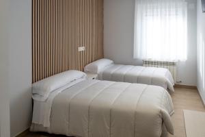 three beds in a room with a window at Hotel La Cortijana in Logroño