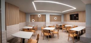 a restaurant with tables and chairs and a tv at Hotel La Cortijana in Logroño