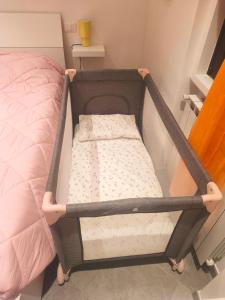 a small crib in a room with a bed at Il Chicco di Arianna in Torre del Lago Puccini