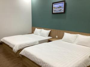 two beds in a hotel room with white sheets at Hotel88 in Ấp Bình Hưng