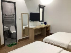 a room with two beds and a desk with a television at Hotel88 in Ấp Bình Hưng